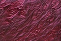 A crinkled satin fabric texture background in deep ruby red. The glossy, textured surface adds depth