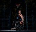 Cripple basketball player in a wheelchair holds a ball on an open gaming ground.