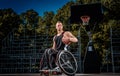 Cripple basketball player in a wheelchair holds a ball on an open gaming ground.