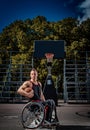 Cripple basketball player in a wheelchair holds a ball on an open gaming ground.