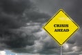 A crisis ahead road sign on a dramatic sky