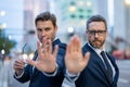 Crisis, risk. Two handsome business men in suit doing stop sing with hand. Warning expression with negative and serious Royalty Free Stock Photo