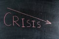 CRISIS word written in red chalk and downward arrow on chalk board Royalty Free Stock Photo