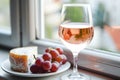 A crisp glass of rose wine sits on a windowsill, accompanied by a plate Royalty Free Stock Photo