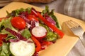 A crisp healthy salad with a fork on a yellow plate with rustic