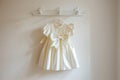 crisp ivory dress with a bow hung on a wallmounted rack Royalty Free Stock Photo