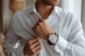 Crisp style man buttoning white shirt, accentuated by a stylish watch