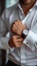 Crisp style man buttoning white shirt, accentuated by a stylish watch