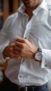 Crisp style man buttoning white shirt, accentuated by a stylish watch