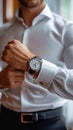 Crisp style man buttoning white shirt, accentuated by a stylish watch