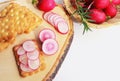 Crispbread with butter and sliced radish on wooden cutting board.