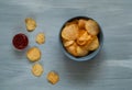 Crisps in a blue bowl with ketchup on a light blue background, space for text.Convenient snack concept