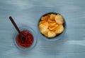 Crisps in a blue bowl with ketchup on a light blue background, space for text.Convenient snack concept