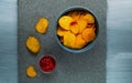 Crisps in a blue bowl with ketchup on a light blue background, top view, space for text.