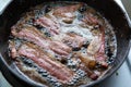 Crispy bacon frying in an iron pan Royalty Free Stock Photo