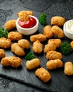 Crispy Battered scampi nuggets with ketchup and mayonnaise on rustic stone board.