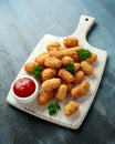 Crispy Battered scampi nuggets with ketchup on white wooden board