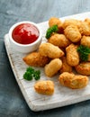 Crispy Battered scampi nuggets with ketchup on white wooden board