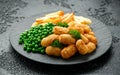 Crispy Battered scampi nuggets served on slate plate with potato chips and green peas Royalty Free Stock Photo