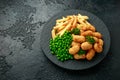 Crispy Battered scampi nuggets served on slate plate with potato chips and green peas Royalty Free Stock Photo