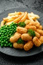 Crispy Battered scampi nuggets served on slate plate with potato chips and green peas Royalty Free Stock Photo