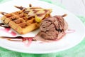 Crispy Belgian waffle with pieces of pear, berry and chocolate syrup and ice cream balls