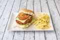 Crispy chicken burger in batter with tomato slice, caramelized onion, sliced cheese, butt mayonnaise and a side of French fries Royalty Free Stock Photo