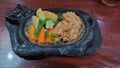 Crispy chicken steak served on a hot plate with some vegetables