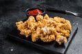 Crispy Fried breadcrumb covered chicken popcorn with ketchup. Black background. Top view