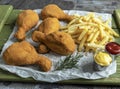 Crispy fried chicken legs breaded golden color, french fries, sauce, wooden background Royalty Free Stock Photo