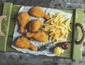 Crispy fried chicken legs breaded golden color, french fries, sauce, wooden background Royalty Free Stock Photo