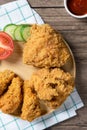 Crispy fried chicken on Round Wood plate served with cucumber, tomato and ketchup on wooden background. Royalty Free Stock Photo