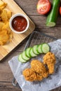 Crispy fried chicken on sieve served with cucumber and potato chips on Wood cutting board served with ketchup. Royalty Free Stock Photo