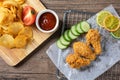 Crispy fried chicken on sieve served with cucumber and potato chips on Wood cutting board served with ketchup. Royalty Free Stock Photo