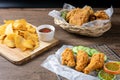 Crispy fried chicken on Sieve and wicker basket serve with cucumber and potato chips on Wood cutting board serve with ketchup. Royalty Free Stock Photo