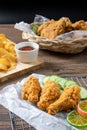 Crispy fried chicken on Sieve and wicker basket serve with cucumber and potato chips on Wood cutting board serve with ketchup. Royalty Free Stock Photo