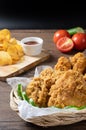 Crispy fried chicken in wicker basket serve with cucumber and potato chips on Wood cutting board serve with ketchup. Royalty Free Stock Photo