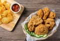 Crispy fried chicken in wicker basket serve with cucumber and potato chips on Wood cutting board serve with ketchup. Royalty Free Stock Photo