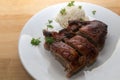 Crispy fried duck breast with rice on a white plate, warm wooden