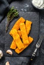 Crispy fried fish fingers with breadcrumbs served with sauce tartar. Black background. Top view