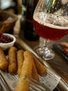 Crispy fried fish fingers on a wooden board with a glass of beer Royalty Free Stock Photo