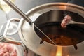 Crispy fried piece of meat on a long fork over a fondue pot with hot oil, convivial dinner often served at New Year for friends Royalty Free Stock Photo