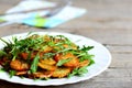 Crispy fried potatoes with arugula on a white plate and wooden table