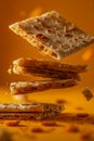 Crispy Golden Pile of Crackers with Pieces Falling in Air on Warm Orange Background