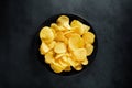 Crispy potato chips on a black plate with black textured background Royalty Free Stock Photo