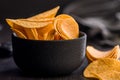 Crispy potato chips in bowl on black table Royalty Free Stock Photo