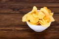 Crispy potato chips in bowl on wooden background, with copyspace