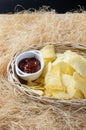 Crispy potato chips in a wicker bowl with ketchup. Royalty Free Stock Photo