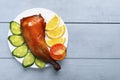 Crispy poultry meat, cooked on a grill with sliced lemon, cucumber and tomatoes on white plate on a wooden table background. Copy Royalty Free Stock Photo