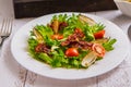 Crispy salad with bacon and cherry on a white plate close-up